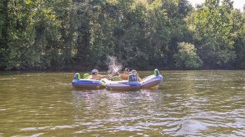 A group of adults sitting in inflatable tubes on a lake cheersing their drinks together causing a splash