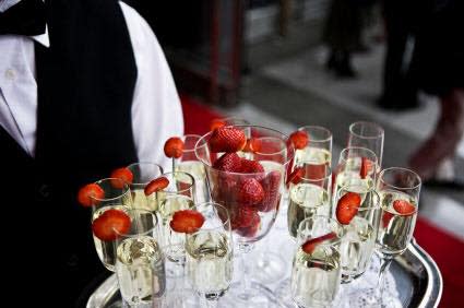 Caterer holding tray of champagne with strawberries