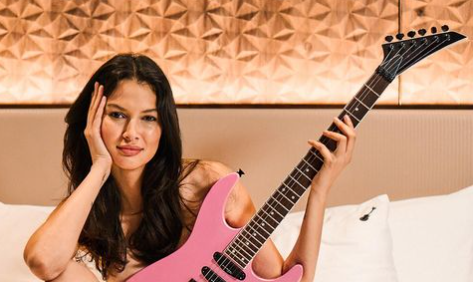Women holding a pink electric guitar