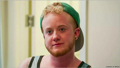 Skyler Jay, the first transgender person featured on Netflix's Queer Eye, in a green baseball cap and tank top