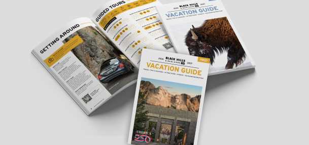 Black Hills & Badlands Vacation Guide with the summer cover, the winter cover, and opened to a page