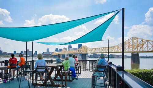 People sitting on the outdoor patio under sun shades at Upland Brewing in Jeffersonville, IN