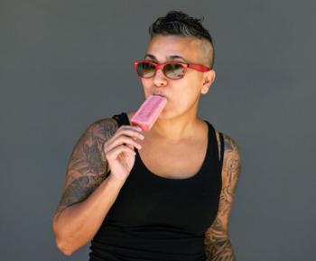 Woman wearing sunglasses eating a popsicle