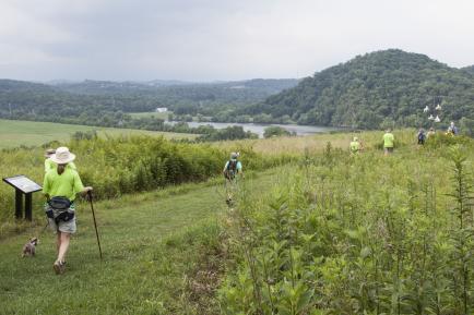 Hikers walk along a grassy trail Seven Islands State Birding Park in Knoxville, TN