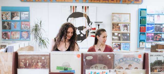 Two women standing in front of records placed on rack at Harvest Records