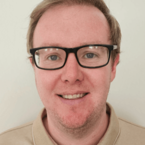 An image of a man smiling and looking directly into the camera.