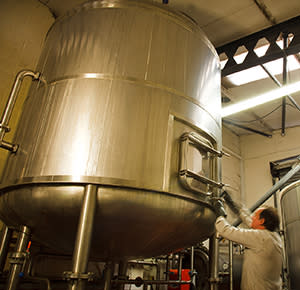Image shows a man checking on a huge vat at Titanic Brewery HQ
