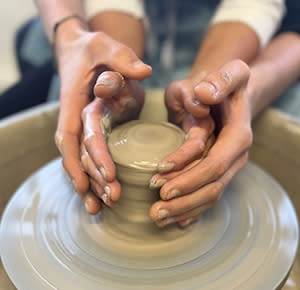 A couple throws a pot together at the potters wheel at World of Wedgwood, Staffordshire