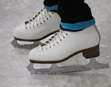 white ice skates with jeans on ice rink