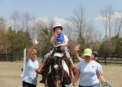Child on horse at therapeutic riding center with volunteers on each side