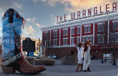 Two young women posing near a big boot in front of the Wrangler Western Wear Store