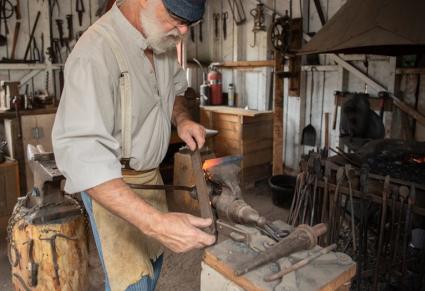 A man blacksmithing in the barn at the Golden History Park in Golden, Colorado.