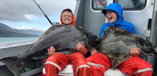 Children holding halibut on a boat