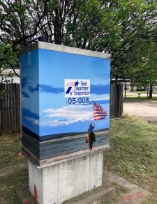 Utility box wrapped in art of woman on a horse holding an American flag