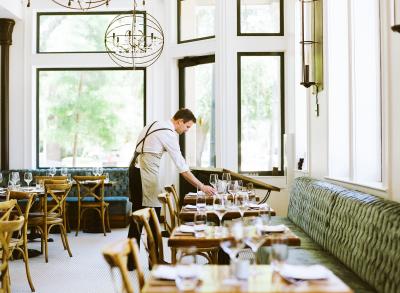 Waiter preparing dinner tables in the Oxlot 9 dining room at the Southern Hotel, Covington