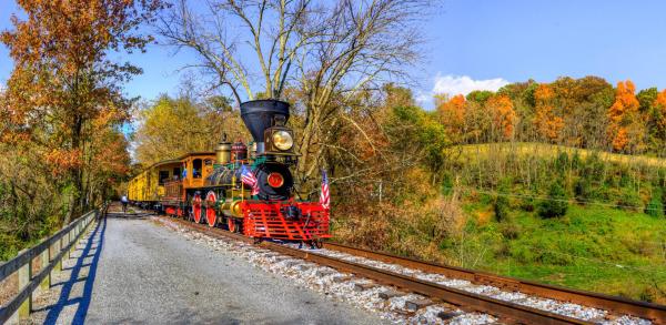 A steam engine makes it's way through a fall scene.