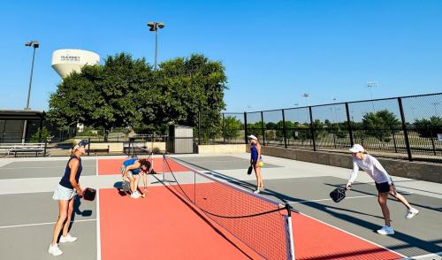 Outdoor pickleball courts at The Courts McKinney - four women on court that is orange and gray