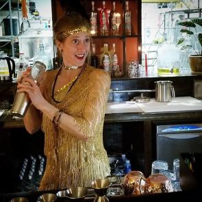 a woman dressed as a 1920's Flapper tending bar at a tasting room