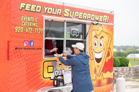 Man reaching for food at the service window of Captain Quesadilla food truck.