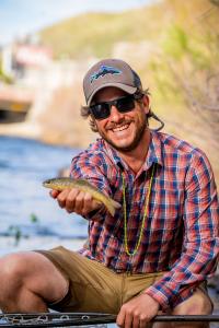 Man holding up a fish he caught in Clear Creek In Golden, CO