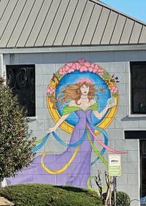 A mural of a beautiful woman in a purple, off-the-shoulder dress