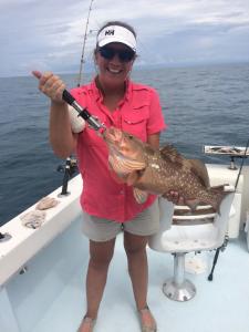 Fishing: woman holding a freshly-caught red grouper fish