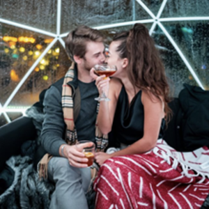 A couple enjoying a date and cocktails inside an igloo on VASO's rooftop patio