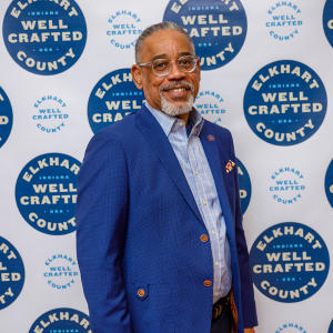 Arvis Dawson poses in front of a white backdrop with the words Elkhart County Well Crafted in blue circles