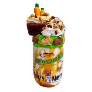 A 24 Karat Cake Milkshake in a mason jar topped with carrot cake, whipped cream, walnuts, cream cheese frosting, and chocolate carrots.
