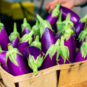 Bright purple eggplant in a wooden basket at the farmers market