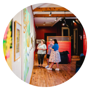 Circular image of people looking at a gallery wall at the Station Arts Centre
