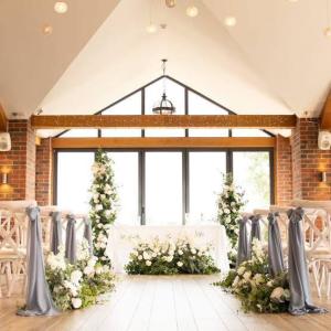 The Boat House at Aston Marina, Staffordshire, decked out for a wedding, with white chair covers, blue ribbons, and light coming in through the huge windows
