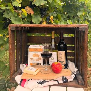 Wooden crate with autumn wines and charcuterie  board with apples, crackers, and cheese in front of Vineyards at Fero Winery in Lewisburg.
