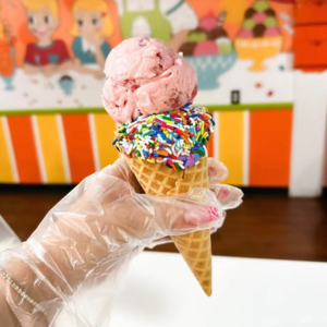 Pink ice cream cone with sprinkles, close-up.
