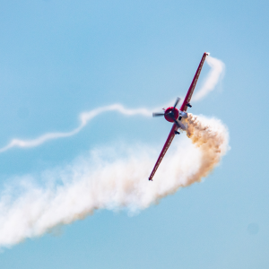 plane flying at airshow with trail of smoke