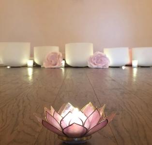A wooden yoga studio floor has a lit candle and some decorative background pillows