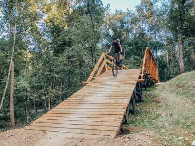 A female mountain biker rides down an angled wooden feature.
