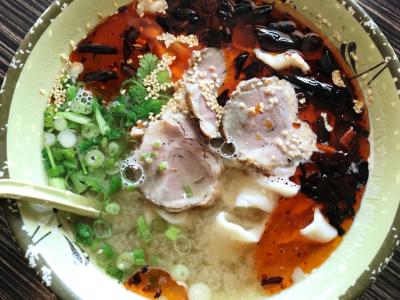 Bird's-eye view into bowl of colorful Asian meat & noodle dish.
