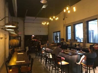 People sitting at bar in Pretentious Brewing's industrial, modern taproom