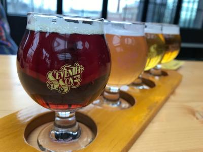 Flight of colorful beers in snifters marked with the Seventh Son Brewing logo