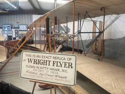 Wright Flyer Replica at the Wings of History Air Museum, with a sign which reads "This is an exact replica of the Wright Flyer flown in Kitty Hawk, N.C. on Dec. 17 1903 piloted by Orval Wright. This model built by Brenton Jones."