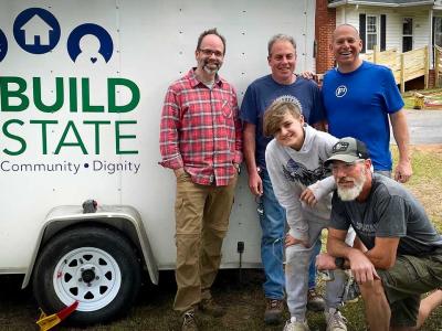 5 volunteers gather around Rebuild Upstate truck