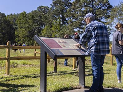 A gentleman looks at the informative sign that describes the moment of battle at the Coal Plantation along the driving tour of Bentonville Battlefield.