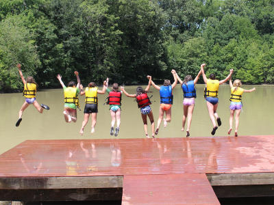 Howell Woods summer camp as kids jump off a dock into the river.