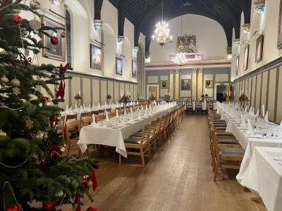Jesus College Hall green Christmas tree to the front left behind that x3 sprigs of banquet tables with white linen