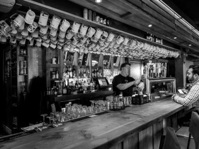 black and white photo of man pouring a draft beer behind a bar