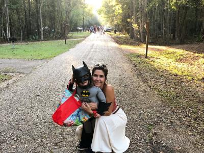 A mother hugs a little boy dressed as Batman on an unpaved road during Trick or Treating at Fontainebleau State Park