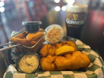 Fish fry basket with French fries, coleslaw and tartar sauce. Next to Guiness beer.