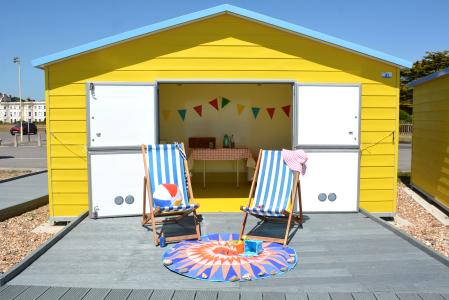 Accessible Beach Hut Littlehampton - a yellow beach hut with double opening doors and a decking area accessed via a ramp.