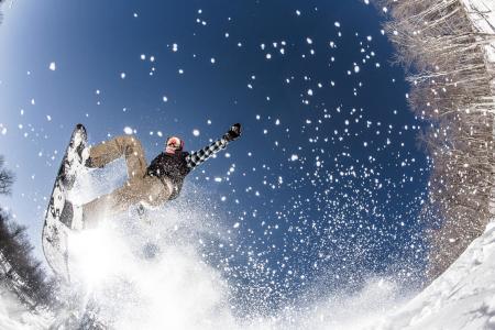 A snowboarder sprays up snow as they carve down a ski slope.